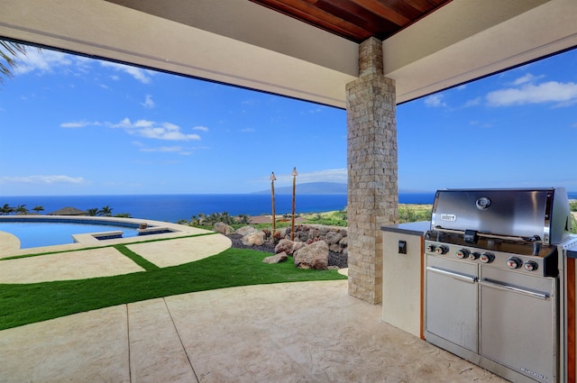 view of patio / terrace with area for grilling, a water view, and an outdoor kitchen