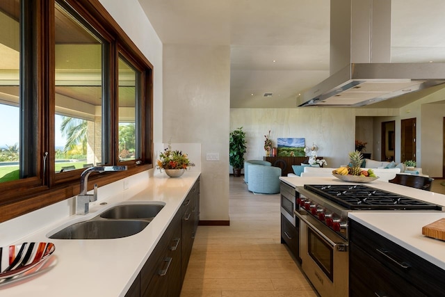 kitchen featuring dark brown cabinetry, extractor fan, sink, range with two ovens, and light hardwood / wood-style flooring