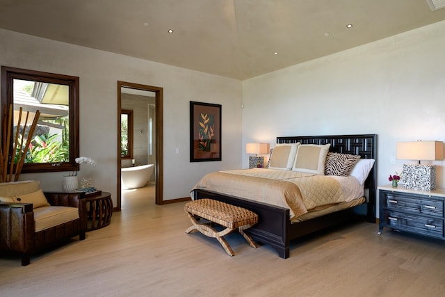 bedroom with connected bathroom and light hardwood / wood-style flooring