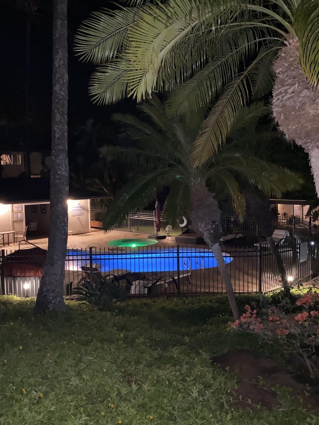 pool at night featuring a patio area