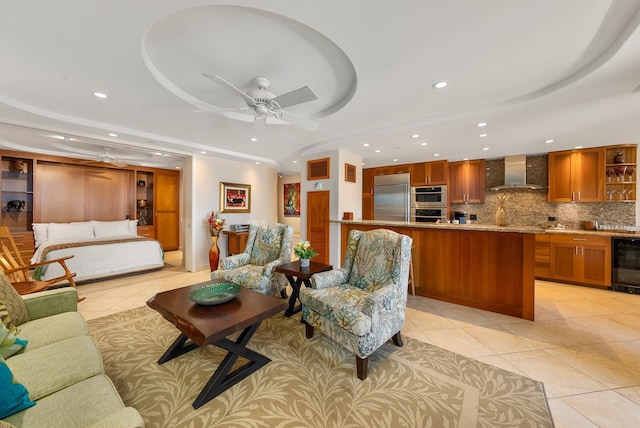 tiled living room featuring beverage cooler, ceiling fan, and a tray ceiling