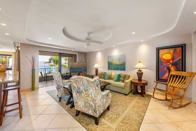 living room with plenty of natural light, a water view, and a tray ceiling