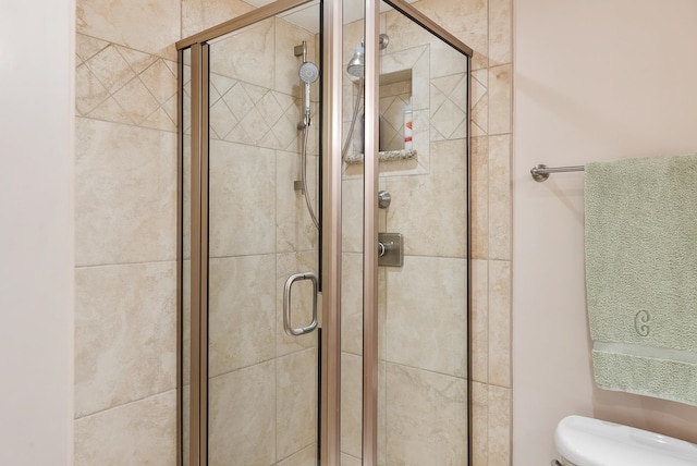 bathroom featuring toilet and a shower with shower door