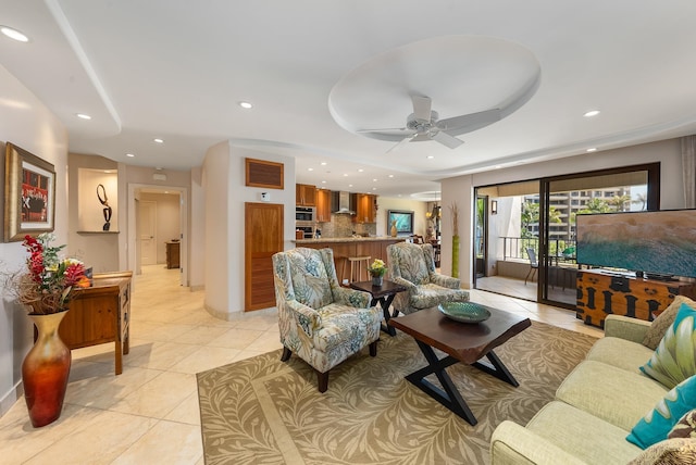 living room featuring a raised ceiling, ceiling fan, and light tile floors