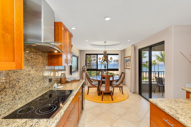 kitchen featuring wall chimney exhaust hood, plenty of natural light, hanging light fixtures, and tasteful backsplash