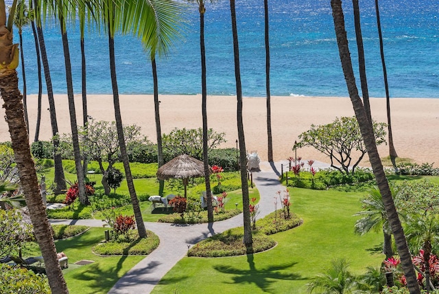 view of property's community featuring a water view, a gazebo, a view of the beach, and a lawn