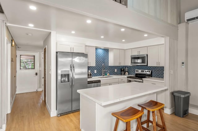 811 S Kihei Rd Unit 2H, Kihei, HI 96753 - kitchen with stainless steel appliances, a sink, light wood-style floors, a breakfast bar, and decorative backsplash