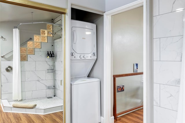 washroom with hardwood / wood-style flooring and stacked washer and clothes dryer