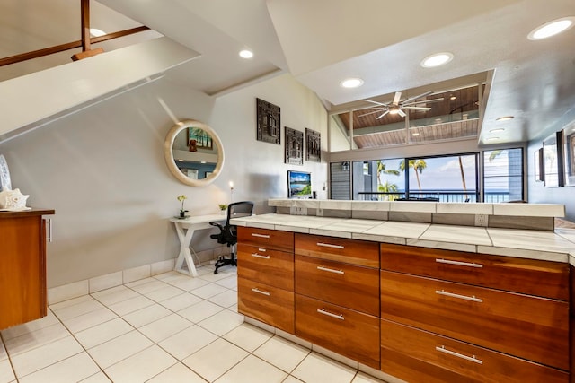 kitchen with tile countertops, ceiling fan, light tile patterned floors, and lofted ceiling