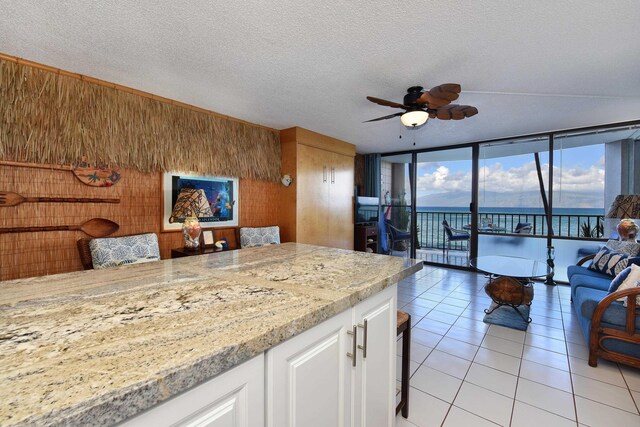 4327 Lower Honoapiilani Rd Unit 207B, Lahaina, HI 96761 - kitchen featuring white cabinetry, ceiling fan, a textured ceiling, wooden walls, and light tile patterned floors