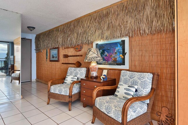 4327 Lower Honoapiilani Rd Unit 207B, Lahaina, HI 96761 - living area with light tile patterned floors, a textured ceiling, and wood walls