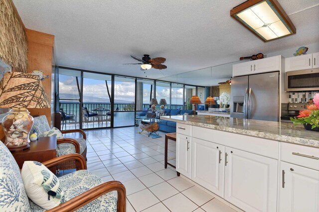 4327 Lower Honoapiilani Rd Unit 207B, Lahaina, HI 96761 - kitchen featuring expansive windows, ceiling fan, a textured ceiling, white cabinetry, and stainless steel appliances