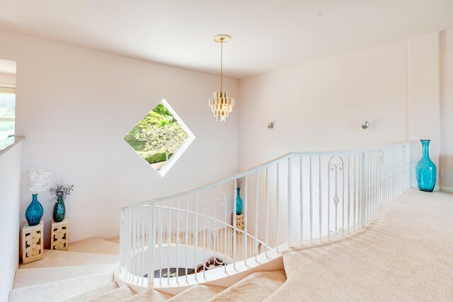 staircase with an inviting chandelier and carpet