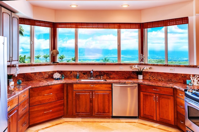 kitchen with plenty of natural light, appliances with stainless steel finishes, sink, and dark stone counters