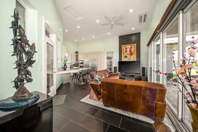 living room with ceiling fan and dark tile patterned floors