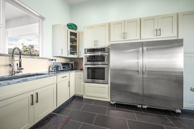 kitchen featuring cream cabinets, stainless steel appliances, dark tile patterned floors, and sink