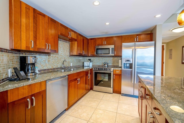 kitchen featuring tasteful backsplash, sink, light stone countertops, stainless steel appliances, and light tile patterned floors