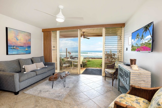 tiled living room with a water view, ceiling fan, and expansive windows