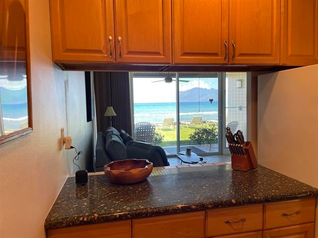 kitchen featuring a water view, a wealth of natural light, dark stone counters, and fridge