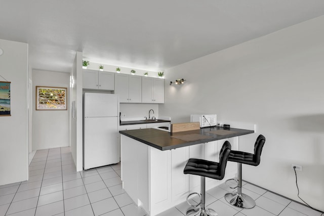 120 Hui Rd F E16, Lahaina, HI 96761 - kitchen with white appliances, dark countertops, a sink, a kitchen breakfast bar, and a peninsula