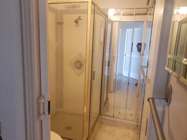 bathroom featuring tile floors, toilet, and a shower with shower door