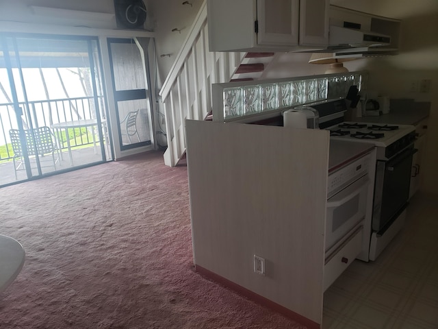 kitchen with light carpet, white range, and white cabinets