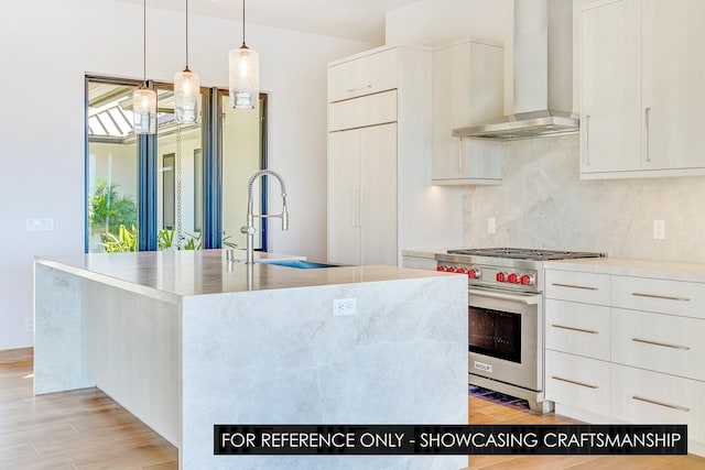 kitchen with wall chimney range hood, designer stove, a sink, and modern cabinets