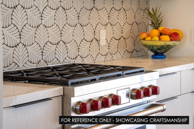 kitchen view of tasteful backsplash, stovetop, and light countertops