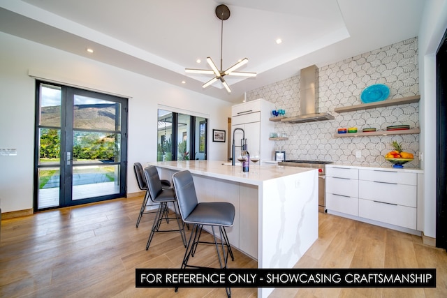 kitchen featuring open shelves, wall chimney range hood, modern cabinets, white cabinets, and tasteful backsplash
