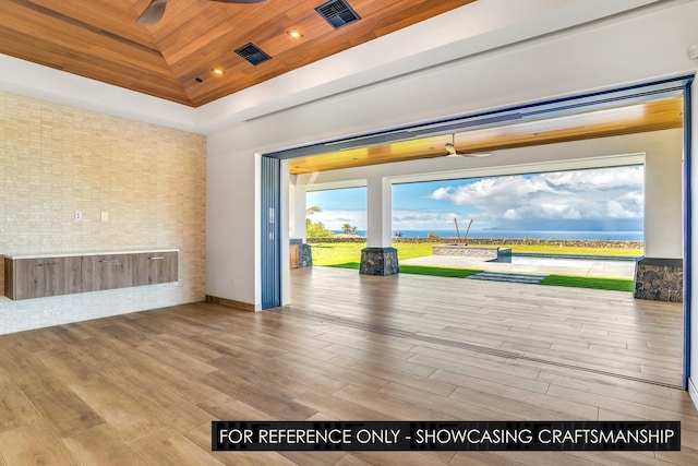 unfurnished room featuring ceiling fan, wood ceiling, wood finished floors, a raised ceiling, and brick wall