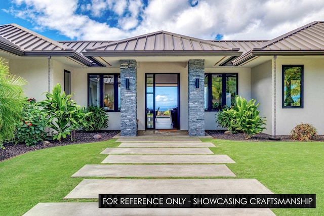 doorway to property with a standing seam roof, stucco siding, metal roof, and a yard
