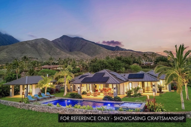 back of property at dusk featuring an outdoor living space, a mountain view, a yard, and roof mounted solar panels