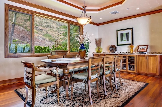 dining room with a tray ceiling, ornamental molding, and hardwood / wood-style flooring