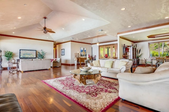 living room with ceiling fan, a raised ceiling, dark wood-type flooring, lofted ceiling, and crown molding