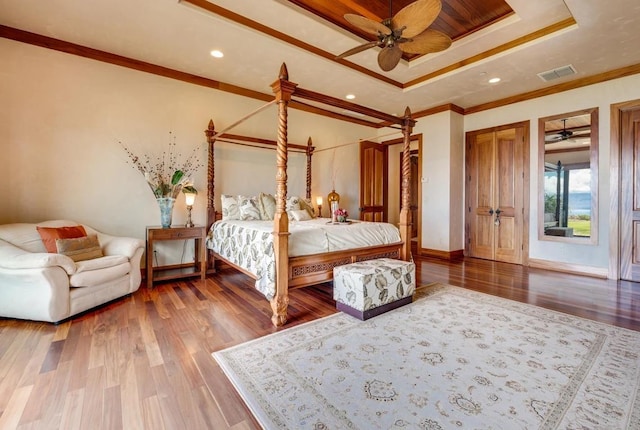 unfurnished bedroom with a raised ceiling, ceiling fan, ornamental molding, and hardwood / wood-style floors