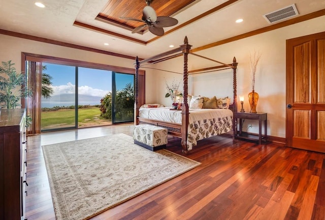 bedroom featuring ceiling fan, dark hardwood / wood-style floors, a tray ceiling, access to exterior, and ornamental molding