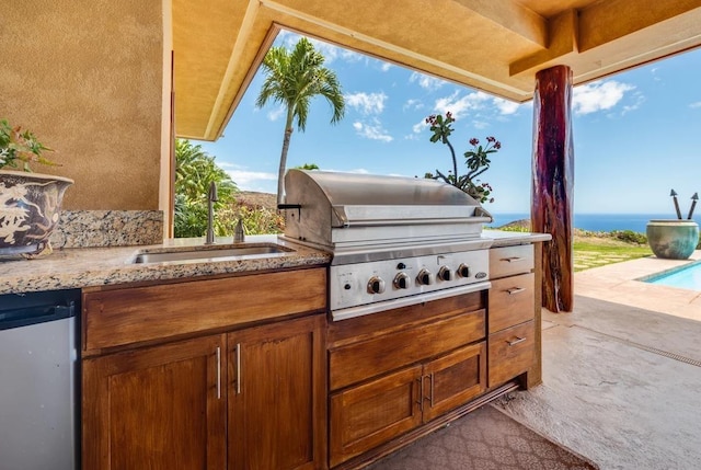 view of patio / terrace featuring sink, a grill, an outdoor kitchen, and a water view