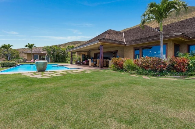 view of pool with ceiling fan, a lawn, and a patio