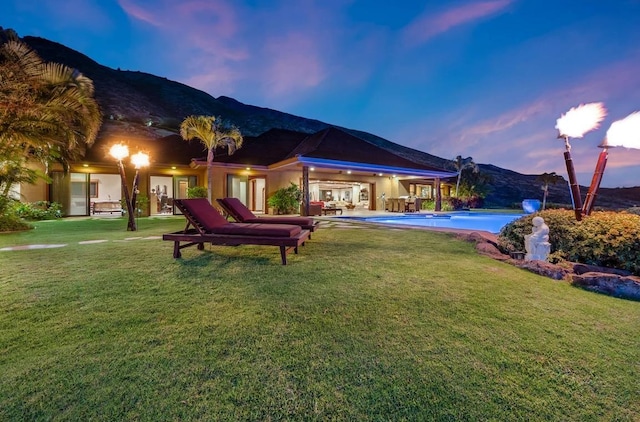 yard at dusk featuring a mountain view and a patio area