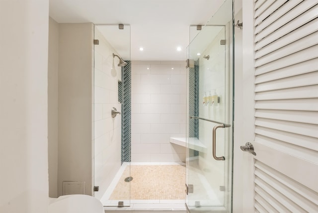 bathroom featuring a shower with shower door and toilet