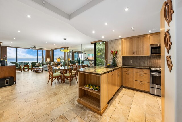 kitchen with kitchen peninsula, backsplash, appliances with stainless steel finishes, expansive windows, and pendant lighting