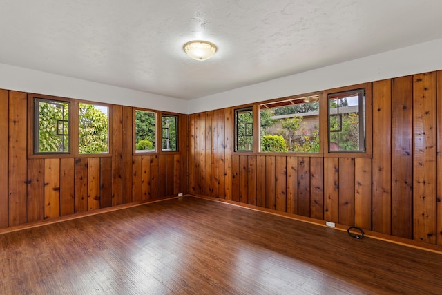 unfurnished room featuring wood walls and dark hardwood / wood-style flooring