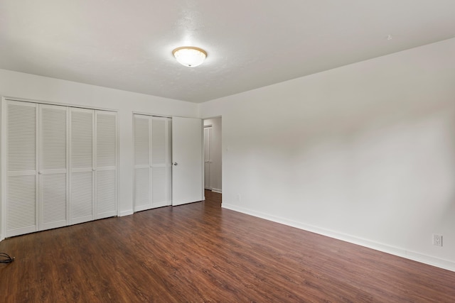 unfurnished bedroom featuring hardwood / wood-style floors and two closets