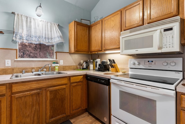 kitchen featuring white appliances, light hardwood / wood-style flooring, vaulted ceiling, and sink