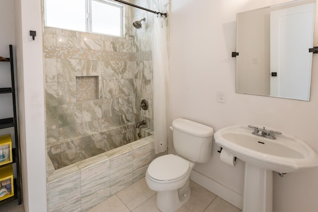 bathroom featuring tiled shower / bath, tile patterned flooring, toilet, and baseboards