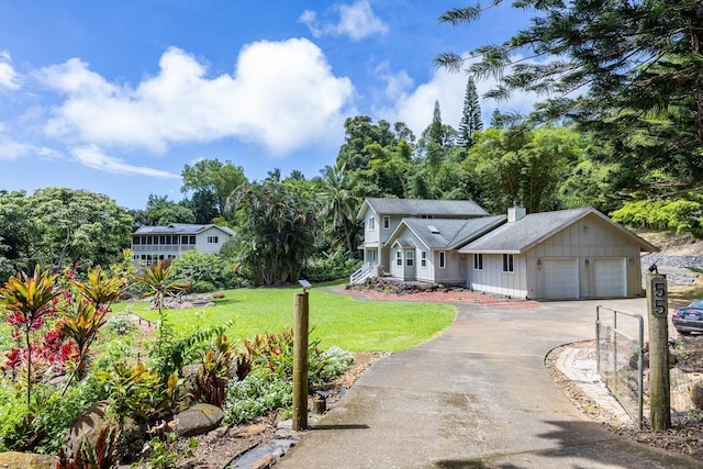 view of front of house featuring driveway, an attached garage, a chimney, and a front lawn