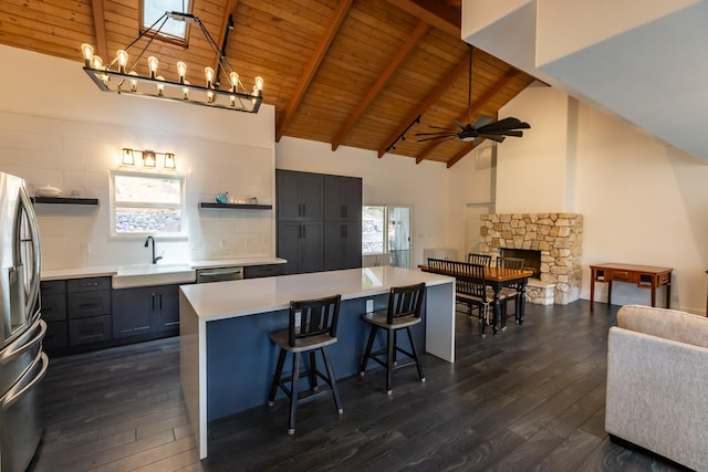 kitchen with a fireplace, open shelves, appliances with stainless steel finishes, wood ceiling, and a sink