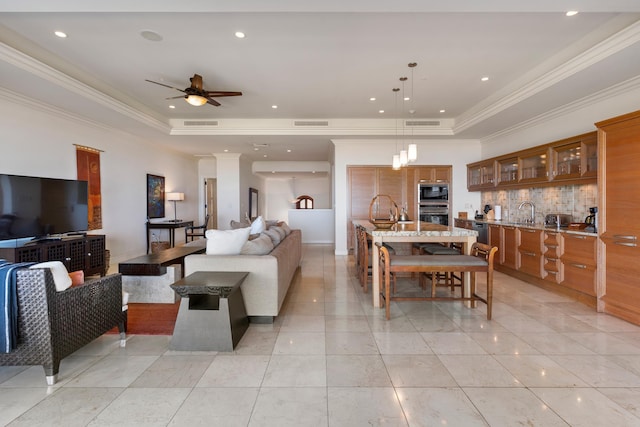 tiled living room with crown molding, a tray ceiling, and ceiling fan