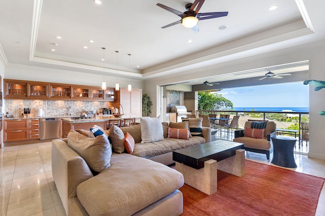 tiled living room featuring a tray ceiling, ornamental molding, and ceiling fan