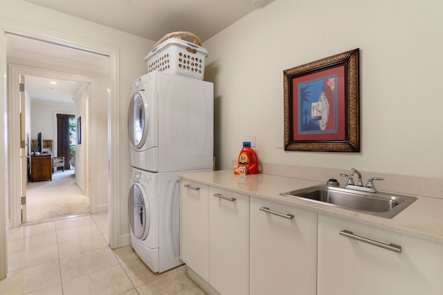 clothes washing area featuring cabinets, stacked washing maching and dryer, sink, and light tile patterned flooring